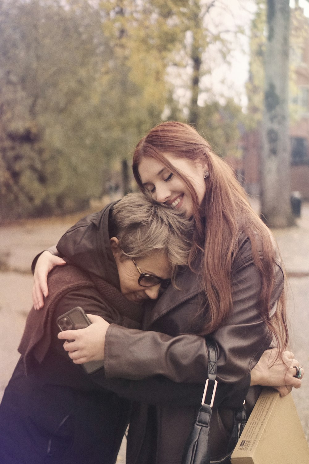 two women hugging each other on a city street