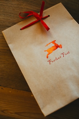 a brown paper bag with a red ribbon on top of it