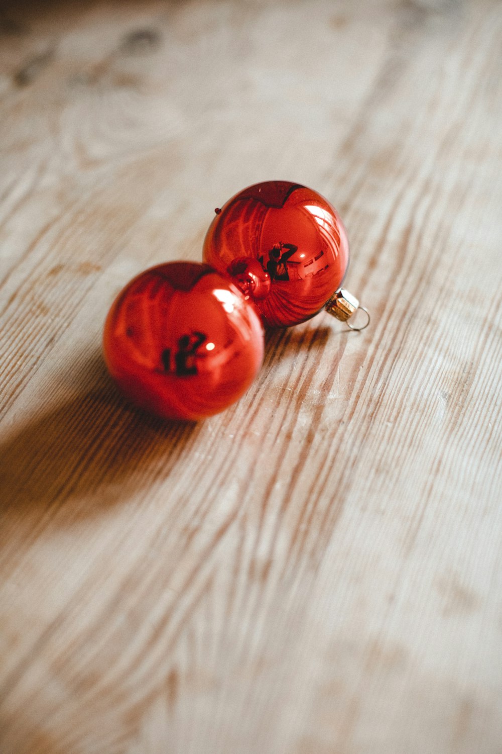 two red ornaments sitting on top of a wooden table
