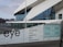 The image depicts a modern architectural building with a geometric design and large glass windows. The foreground shows signage with the word 'eye' and a list of facilities available, such as museum, film, shop, and restaurant. The background includes a waterfront view with additional buildings under a cloudy sky.
