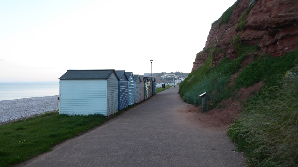 a path next to a beach with a row of beach huts on the side of