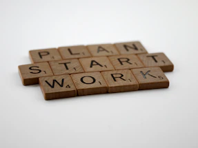 two scrabble tiles spelling the word plan, start, work