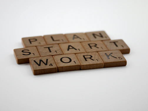 two scrabble tiles spelling the word plan, start, work