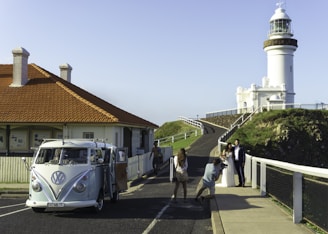 a white vw bus parked next to a white lighthouse