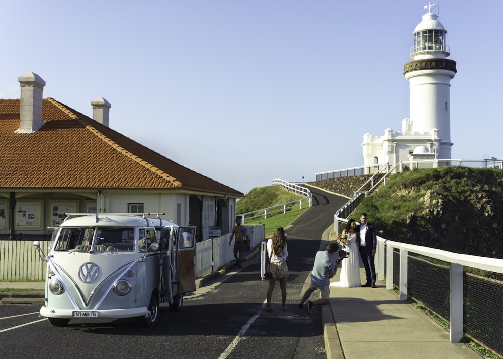 a white vw bus parked next to a white lighthouse