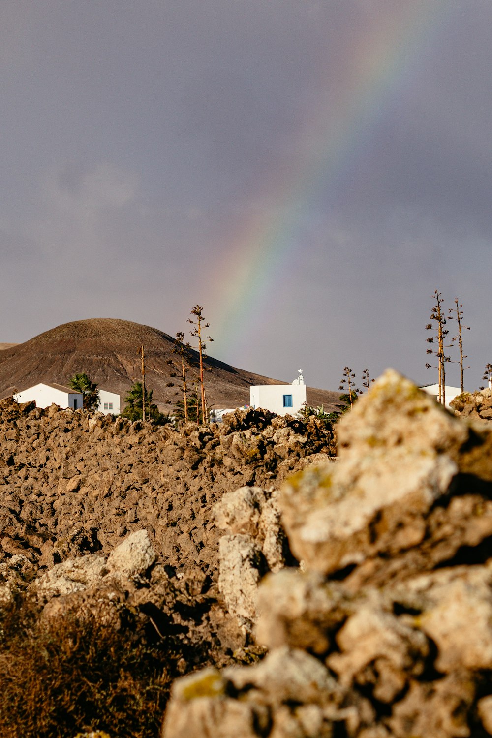a rainbow in the sky over a rocky hillside
