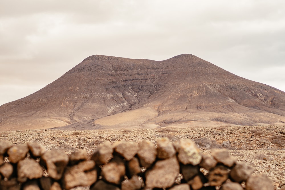 a stone wall in front of a mountain