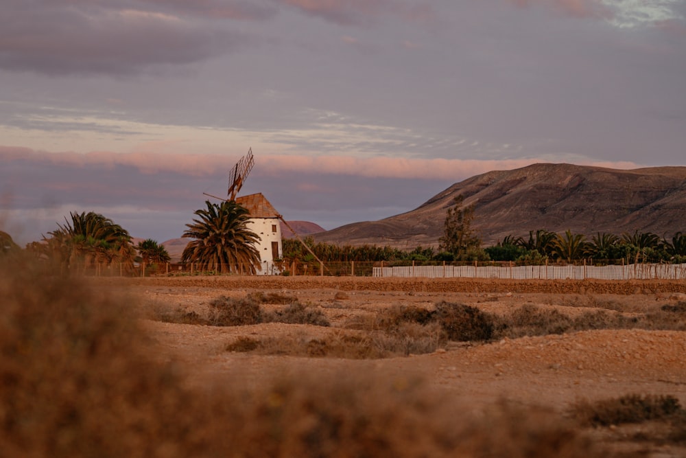 a windmill in the middle of a desert with mountains in the background