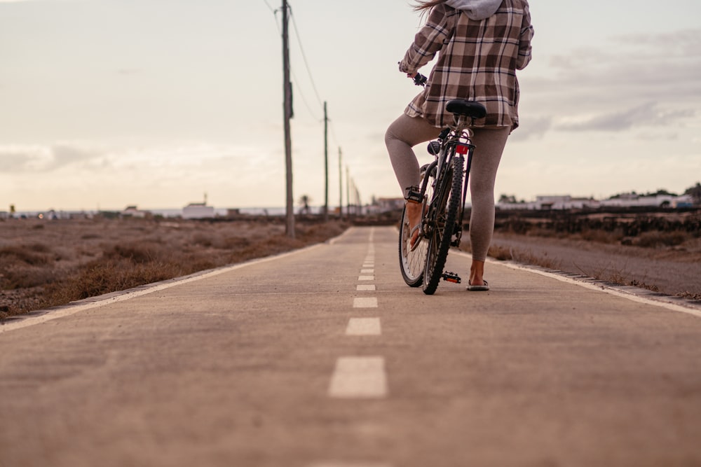 a woman riding a bike down a road