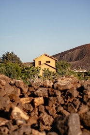 a yellow house sitting on top of a pile of rocks