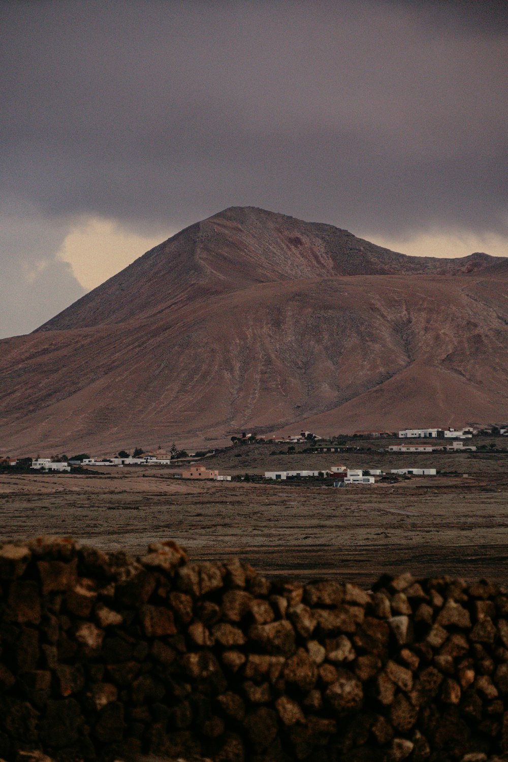 a large mountain with a small town in the distance