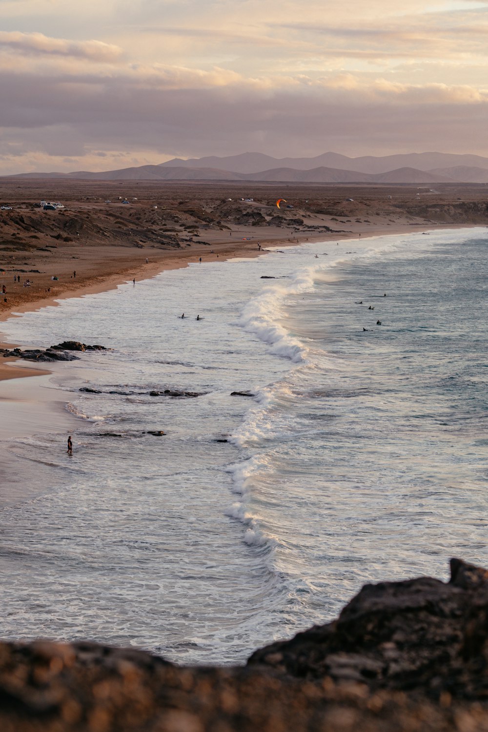 a group of people standing on top of a beach next to the ocean