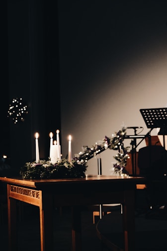 a wooden table topped with candles next to a piano