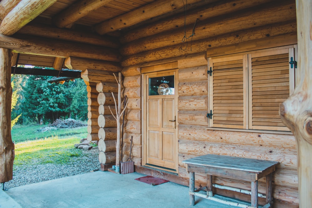 a wooden cabin with a bench and windows