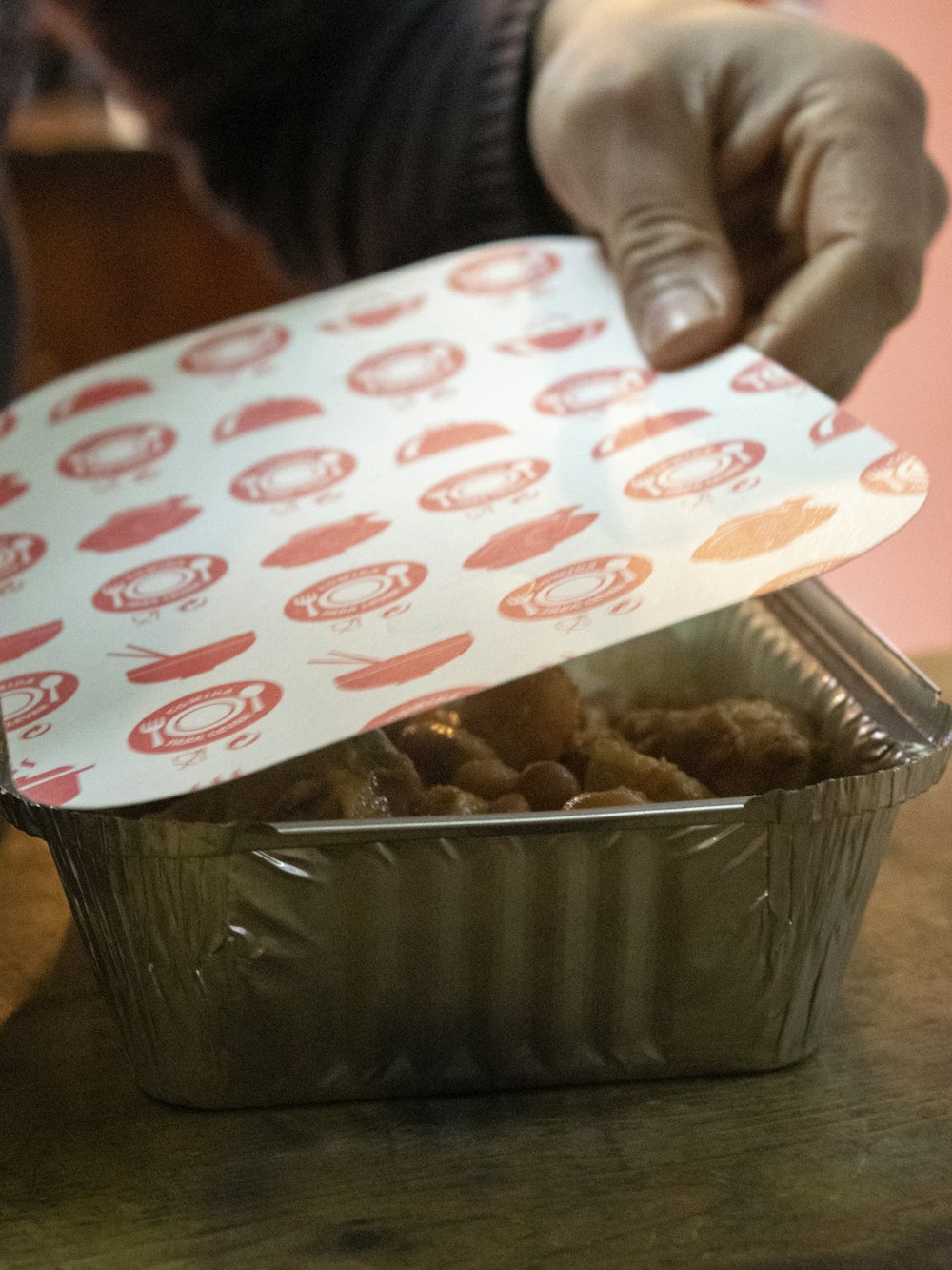 a person holding a piece of paper over a container of food