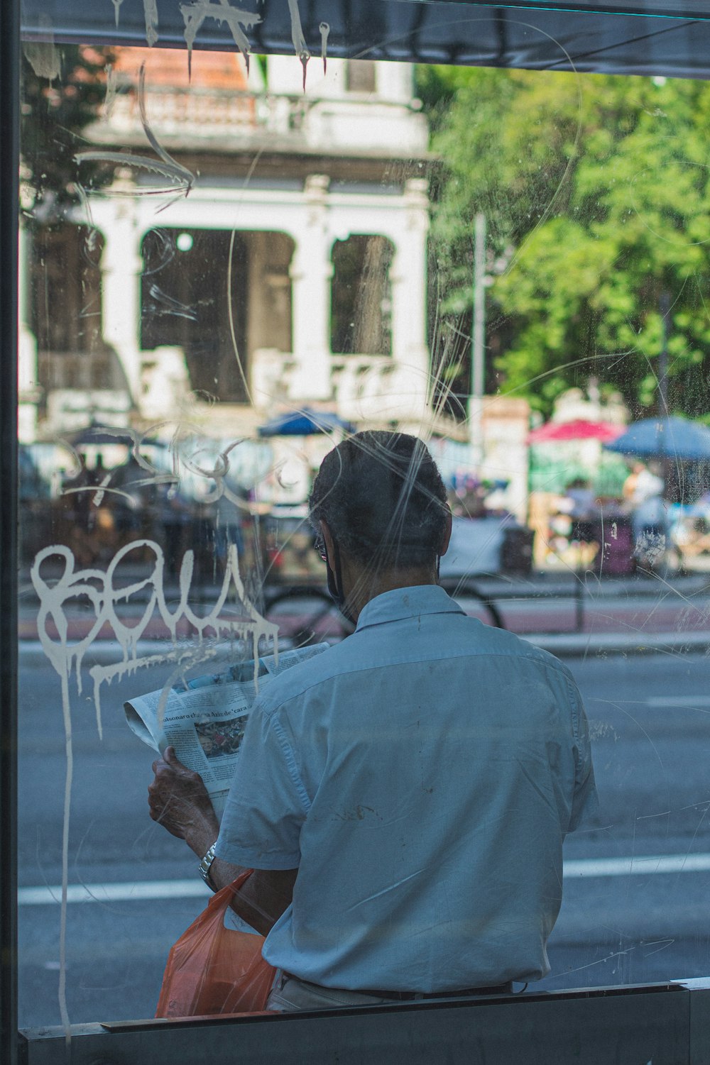 a man sitting on a bench reading a newspaper