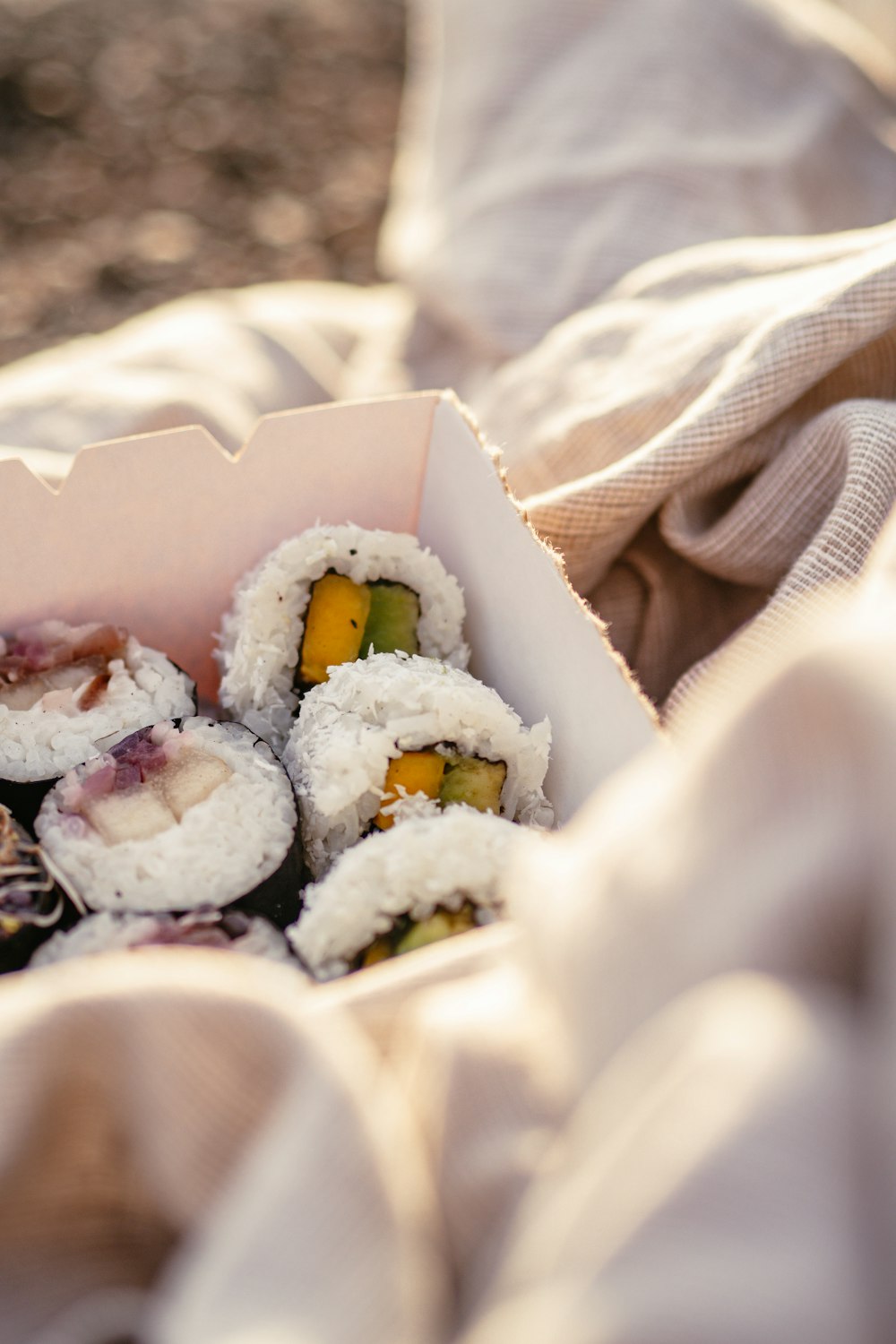 a box filled with sushi sitting on top of a bed