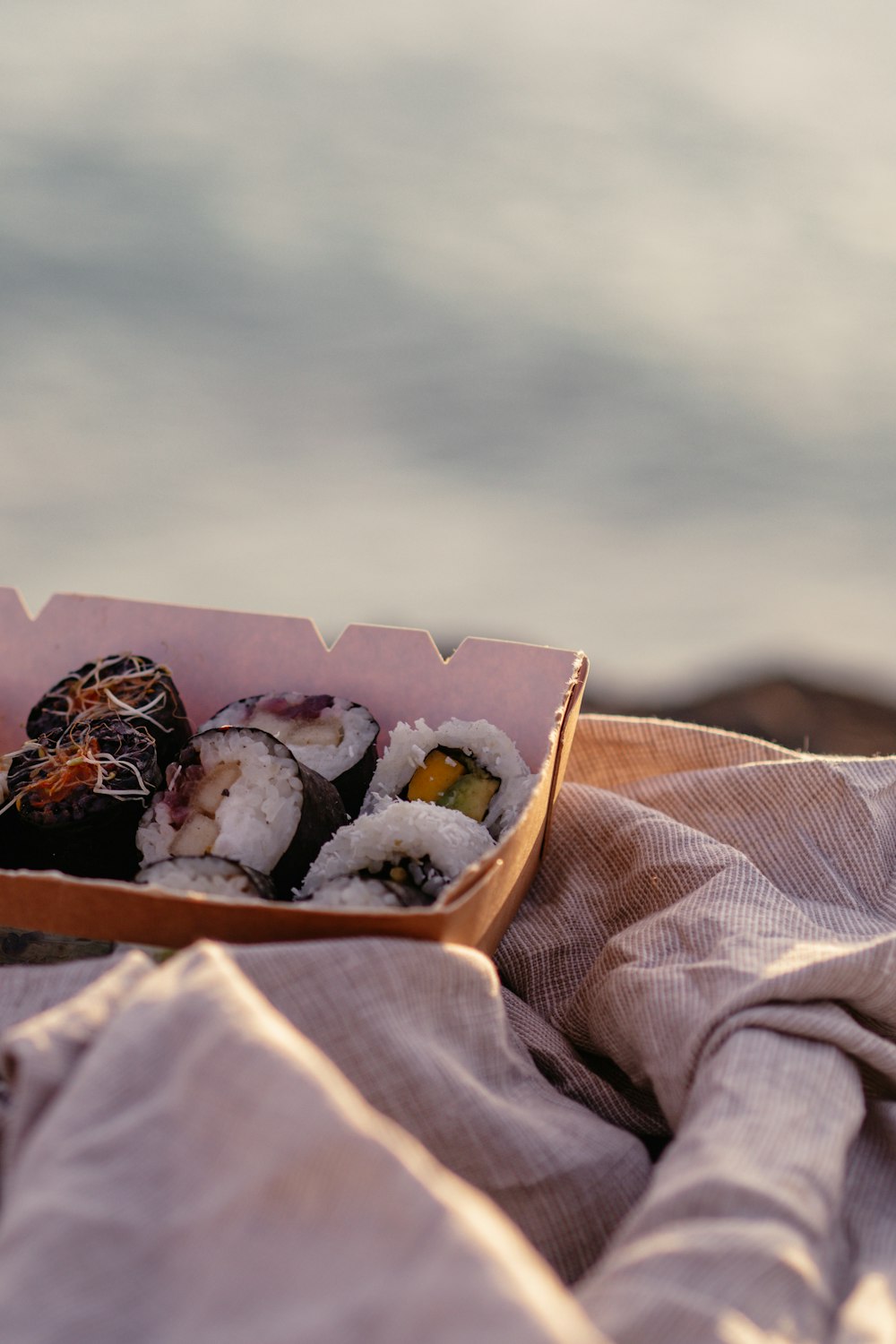 a box of sushi sitting on top of a bed