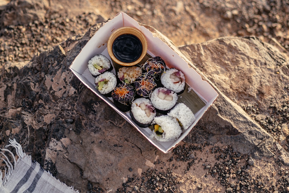 a box of sushi on a rocky surface