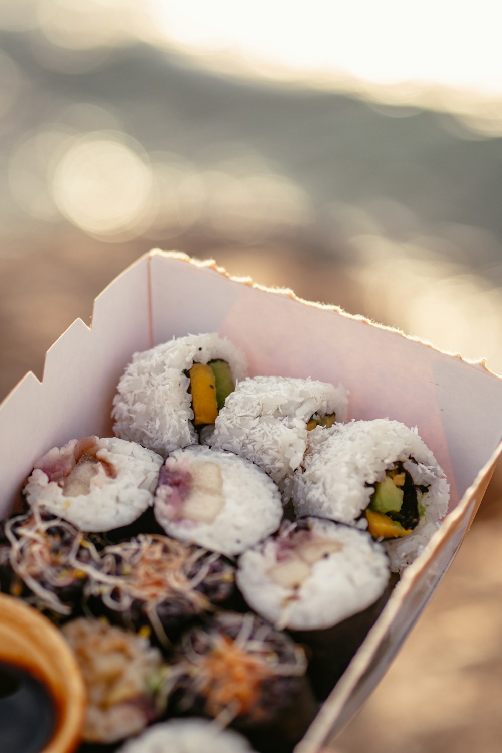 a person holding a box of sushi