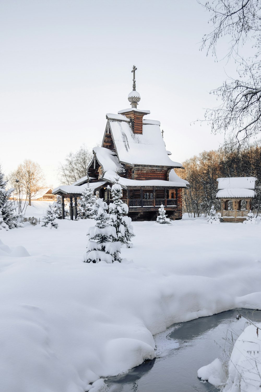 a house covered in snow next to a river