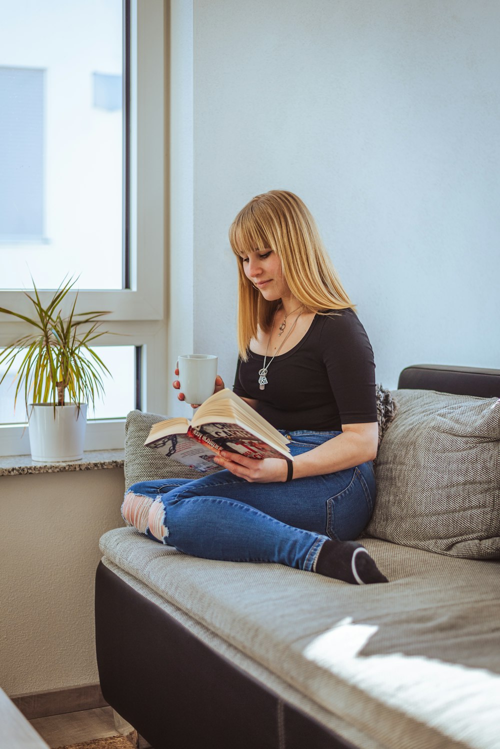 a woman sitting on a couch reading a book