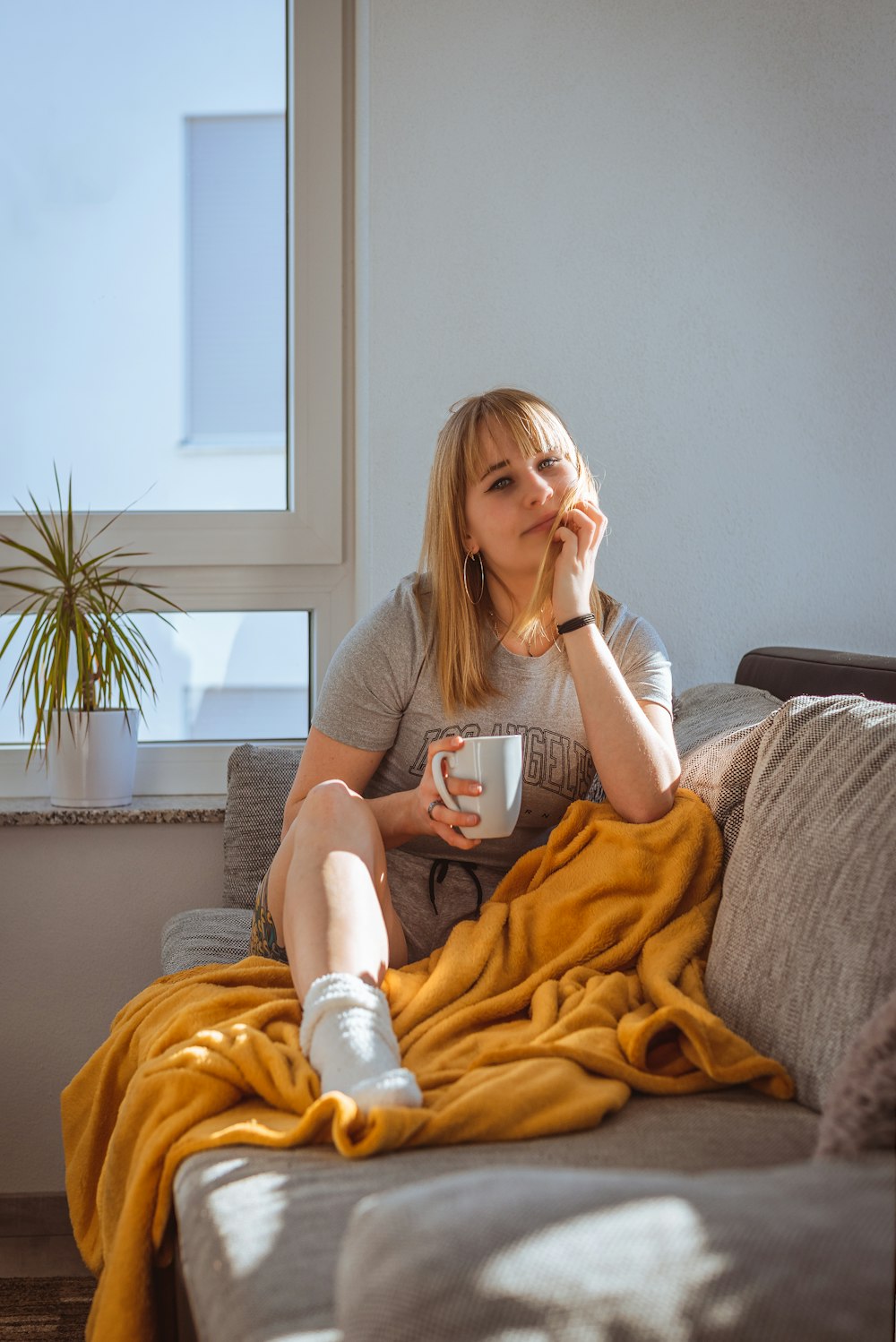 a woman sitting on a couch holding a cup of coffee