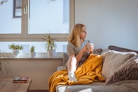 a woman sitting on a couch holding a glass of water