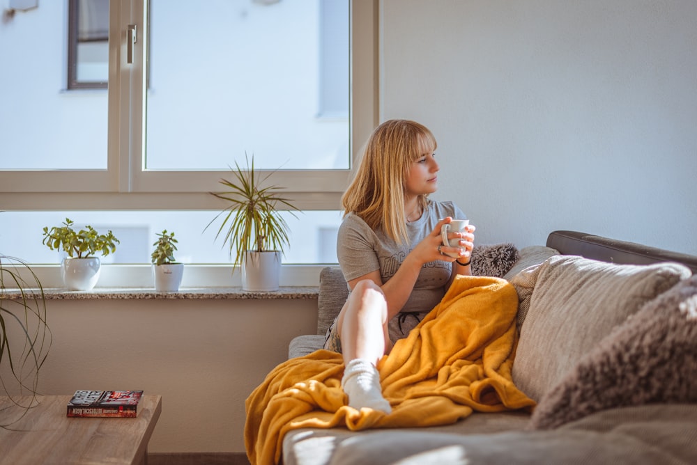 Eine Frau sitzt auf einer Couch und hält ein Glas Wasser in der Hand