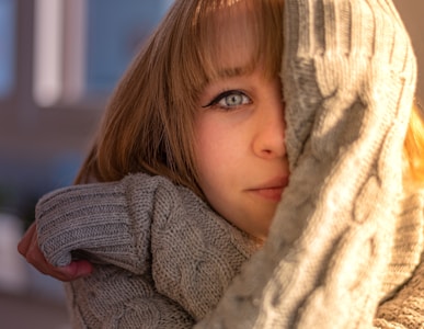 a little girl wearing a sweater and a scarf