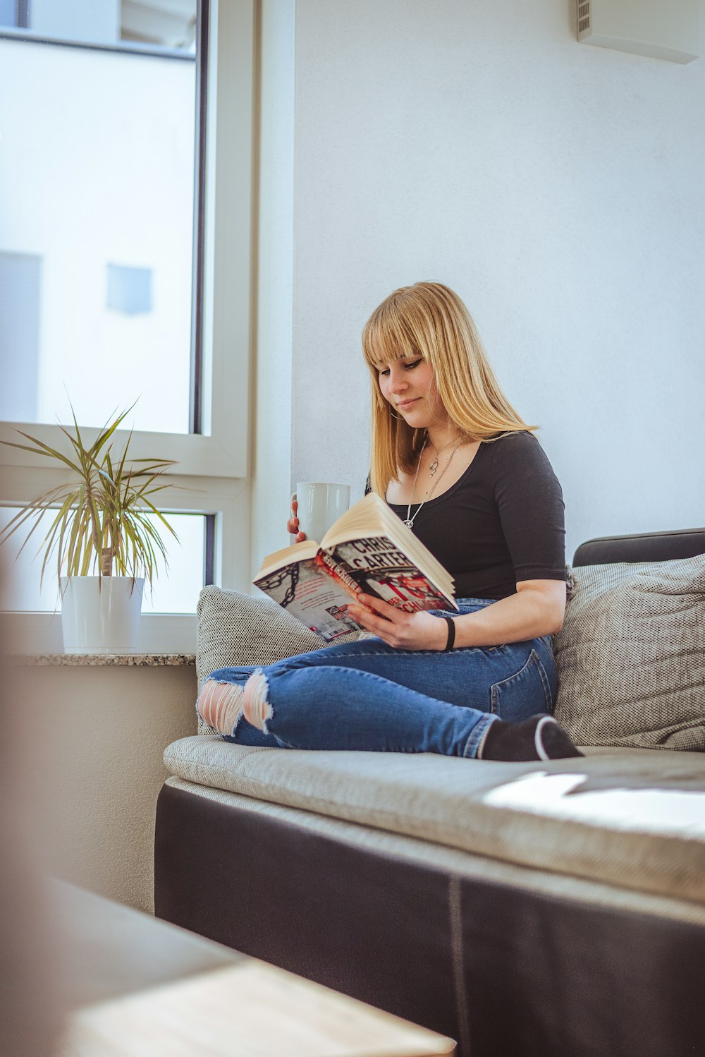 a woman sitting on a couch reading a book