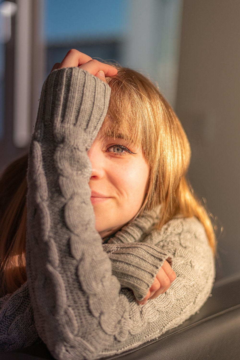 a woman sitting on a couch wearing a gray sweater