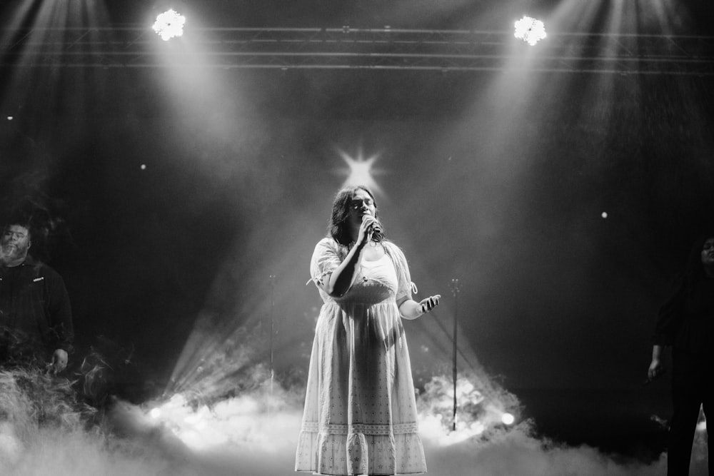 a woman standing on a stage holding a microphone