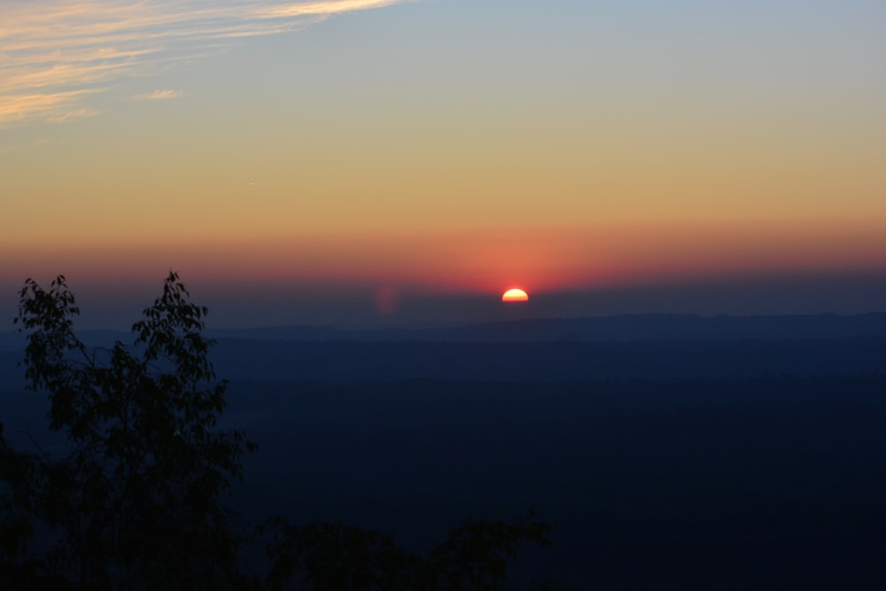 the sun is setting over a mountain range