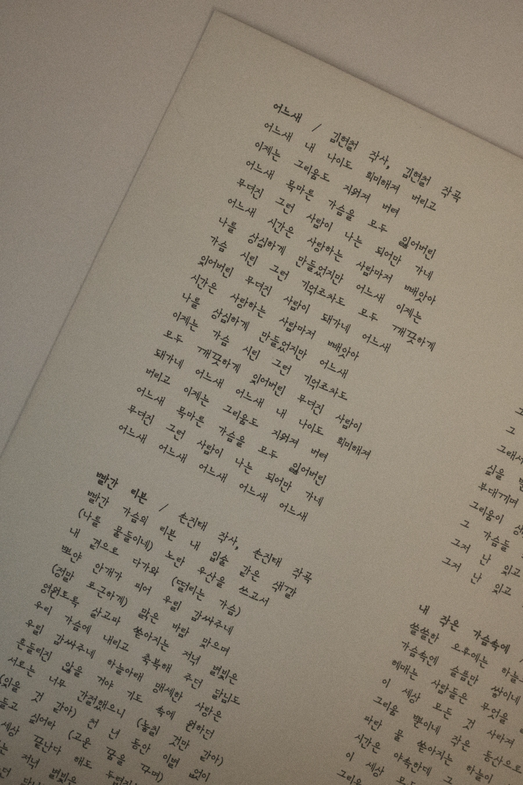 A sheet of paper printed with short columns of Korean text, photographed at an angle
