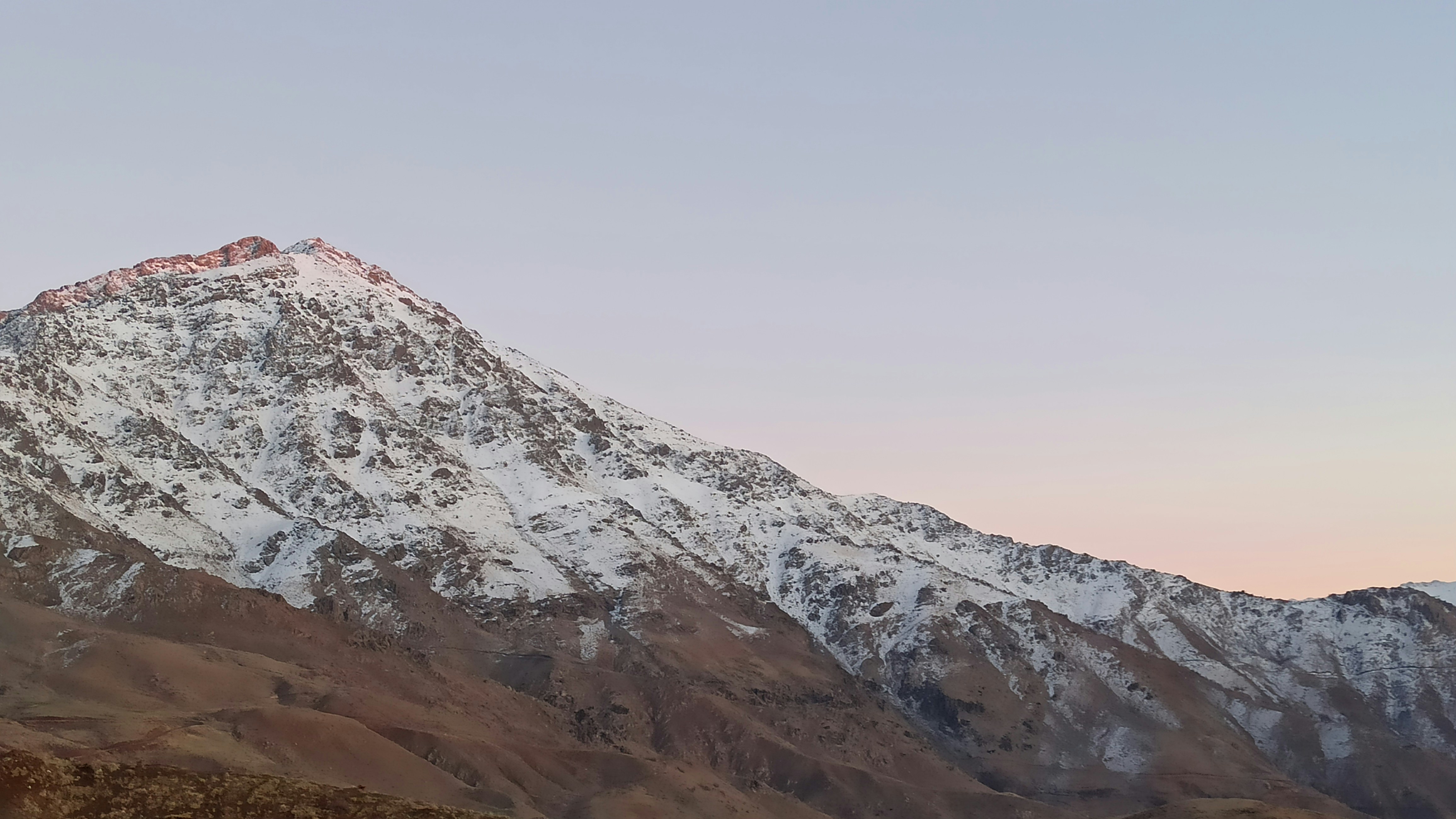 a snow covered mountain with a pink sky in the background