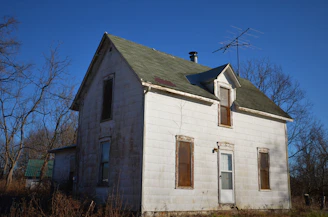 an old white house with a green roof