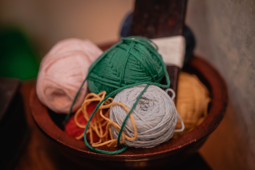 balls of yarn are in a bowl on a table