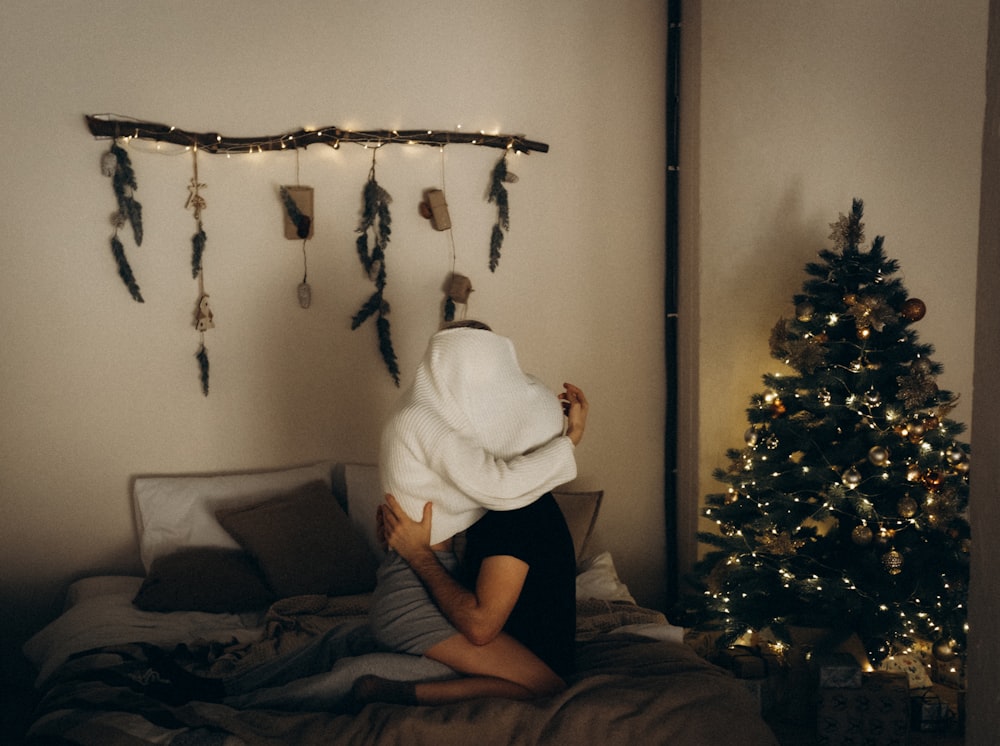 a woman wrapped in a blanket sitting on a bed