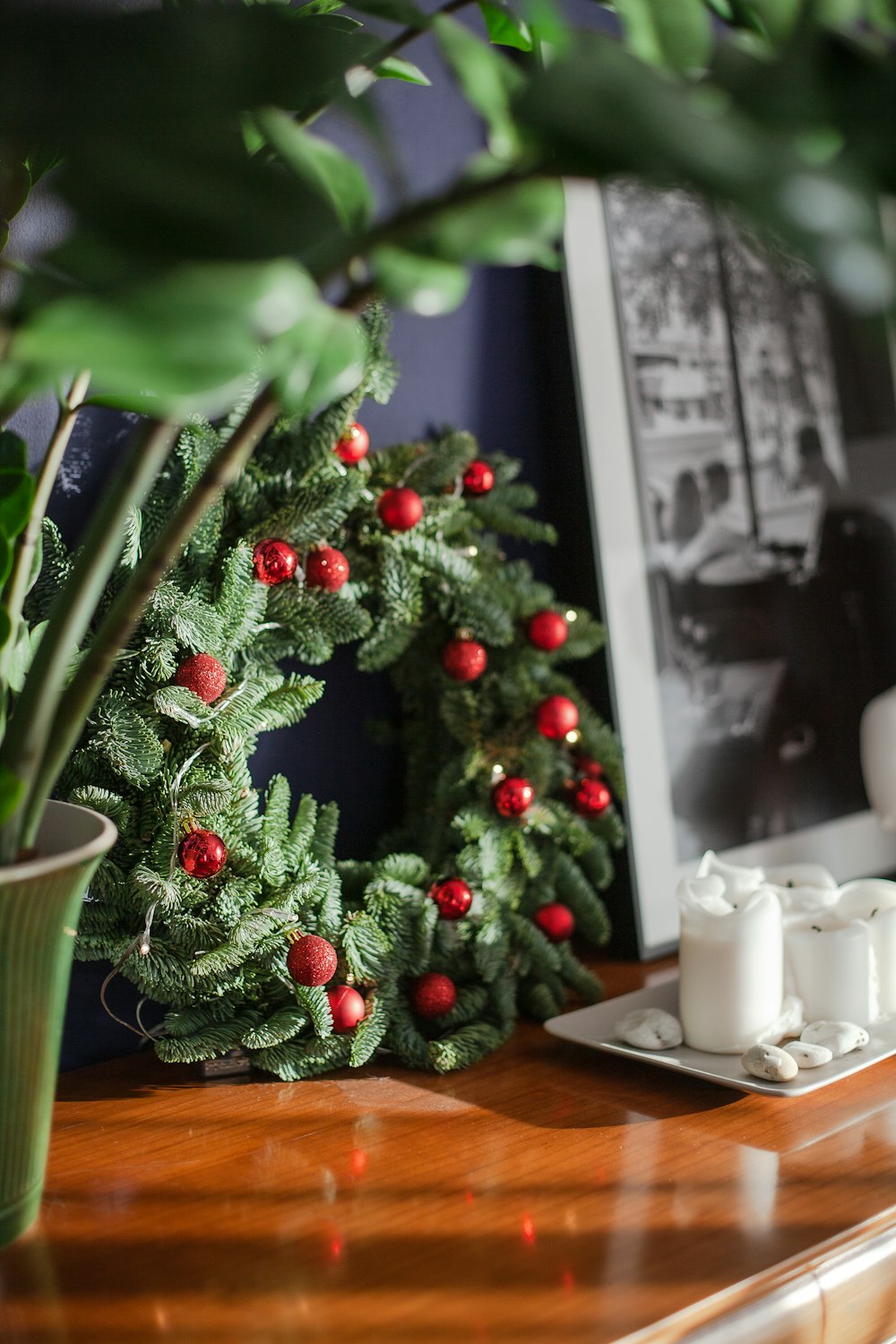 a christmas wreath sitting on top of a table next to a potted plant