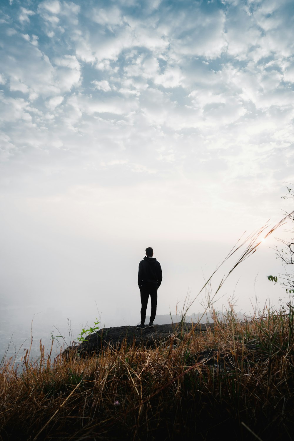 a man standing on top of a hill overlooking a body of water