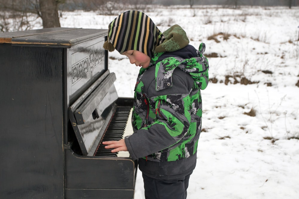 a young boy playing a piano in the snow