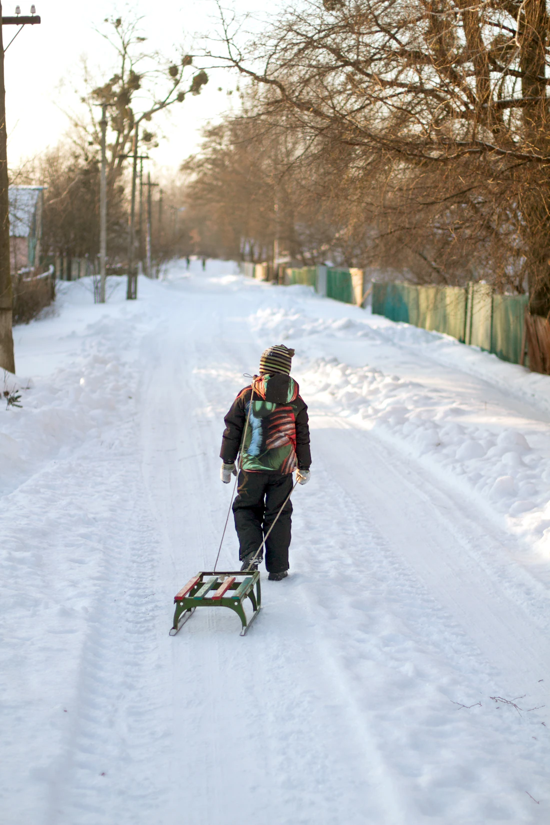 Jongetje trekt een slee over een besneeuwde weg