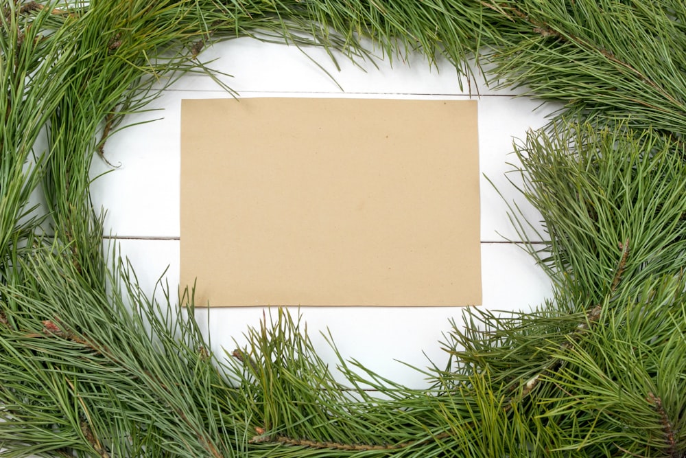 a square piece of paper sitting on top of a green wreath