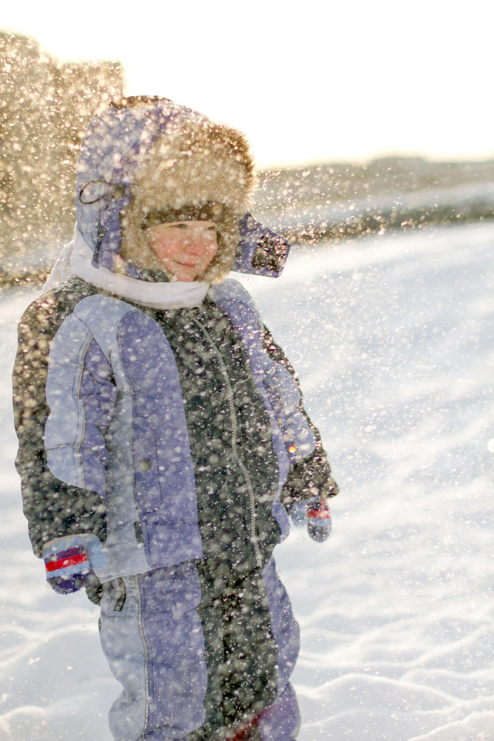 Ein kleiner Junge, der mit einem Snowboard im Schnee steht