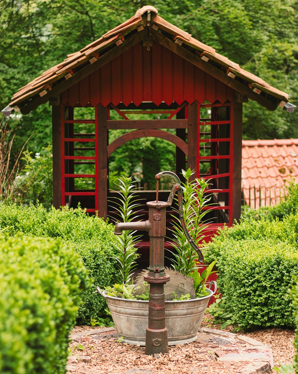a water fountain in a garden with a gazebo in the background