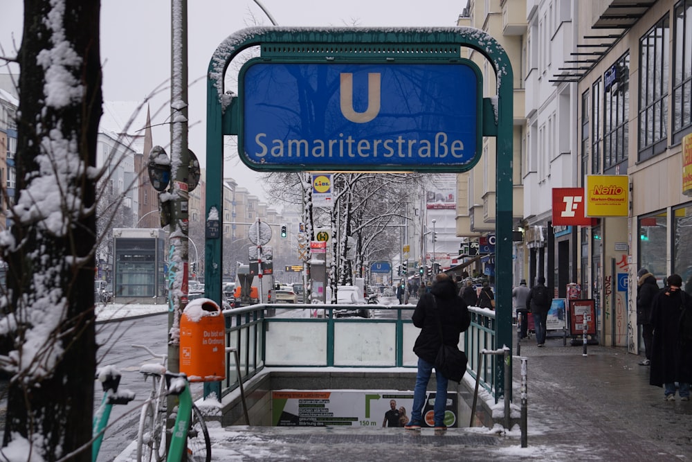 a man standing on a sidewalk next to a blue sign