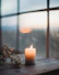 Close-up of a softly glowing candle surrounded by natural dried flowers on a wooden table.