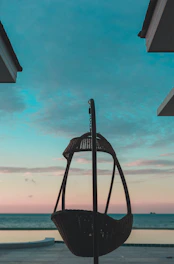 a swing sitting on top of a wooden floor next to the ocean