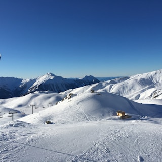 Snow-covered ski hill with luxury chalets in the background under clear blue sky.